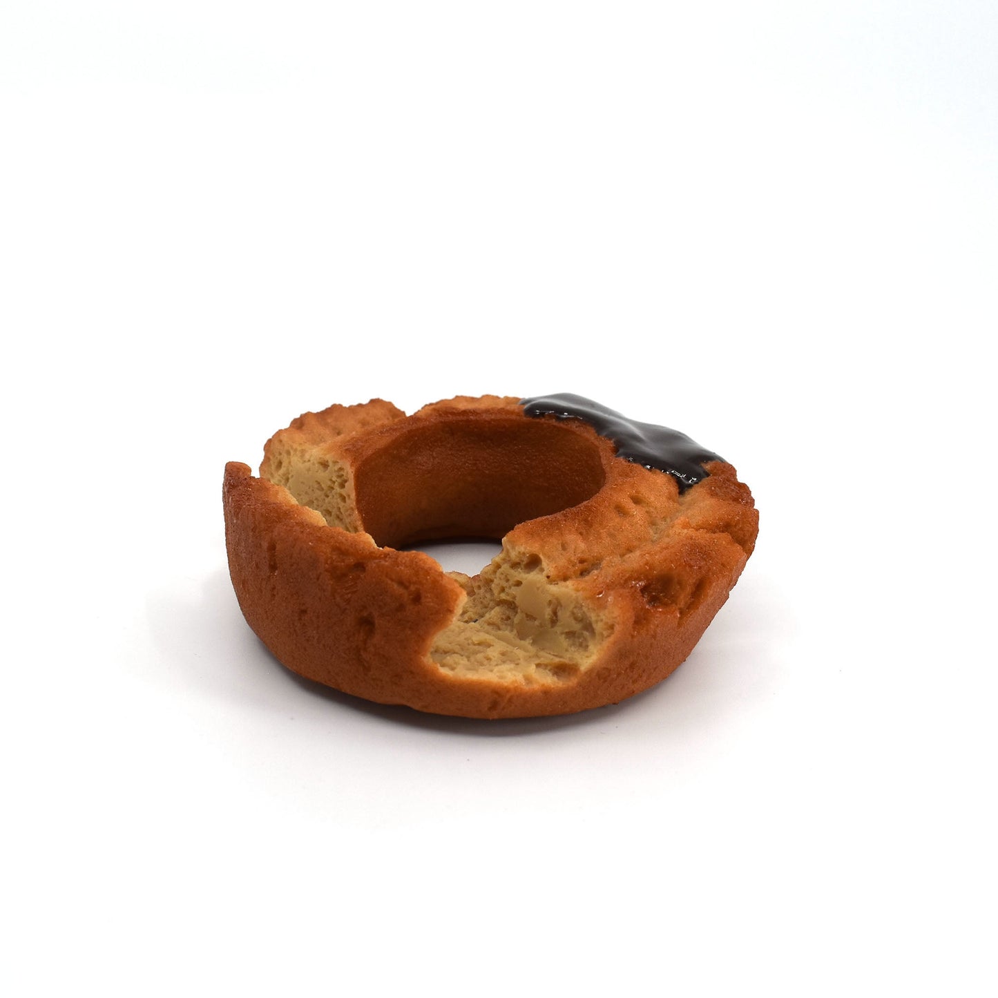 Close-up of a chocolate-glazed donut-shaped phone holder with a bite mark, designed to resemble a real pastry, resting on a white background.