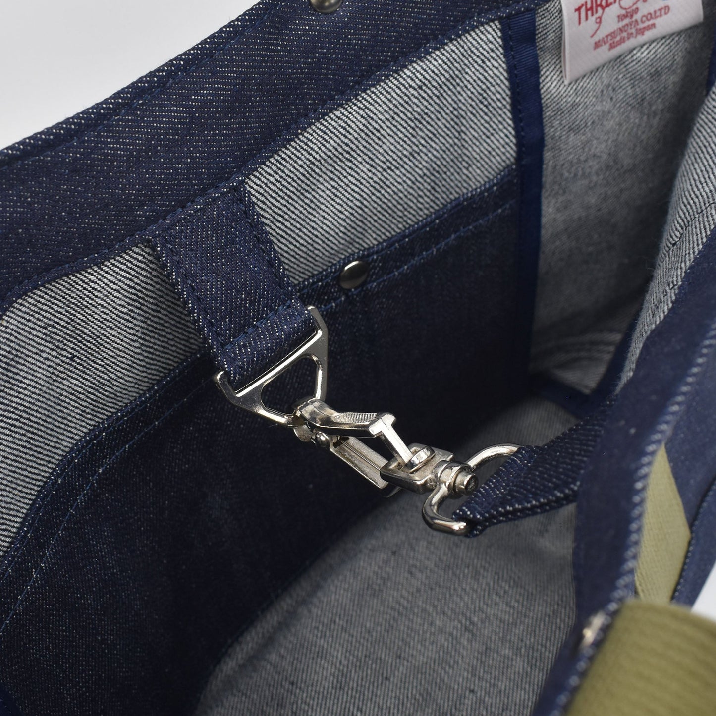 Close-up of interior of Japanese denim tote showing silver snap hook clasp, pocket stitching, and high-quality selvage fabric lining