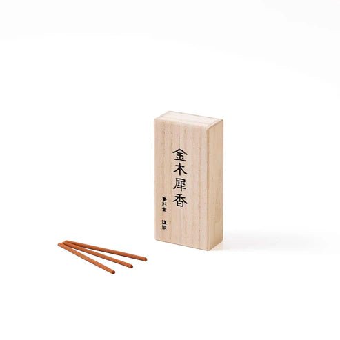 Three orange incense sticks beside a wooden box labeled with Japanese characters for Osmanthus Incense