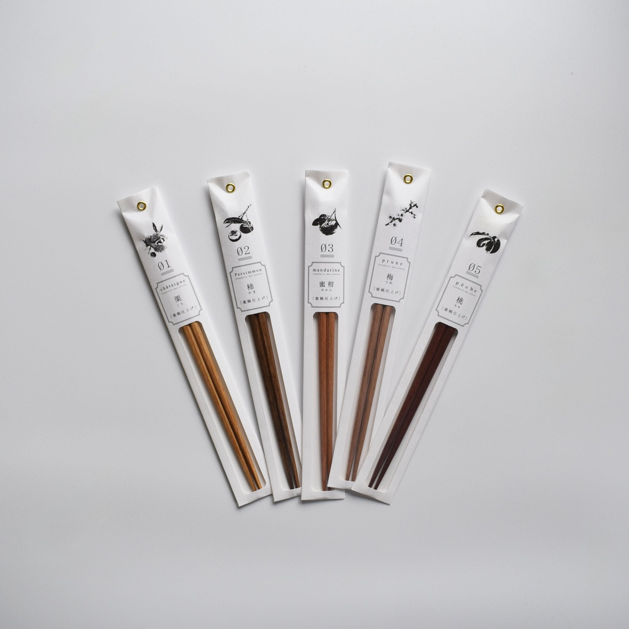 Set of five Tetoca Japanese wooden chopsticks in individual white paper sleeves, each with a botanical illustration and Japanese text, arranged in a fan shape on a light background.