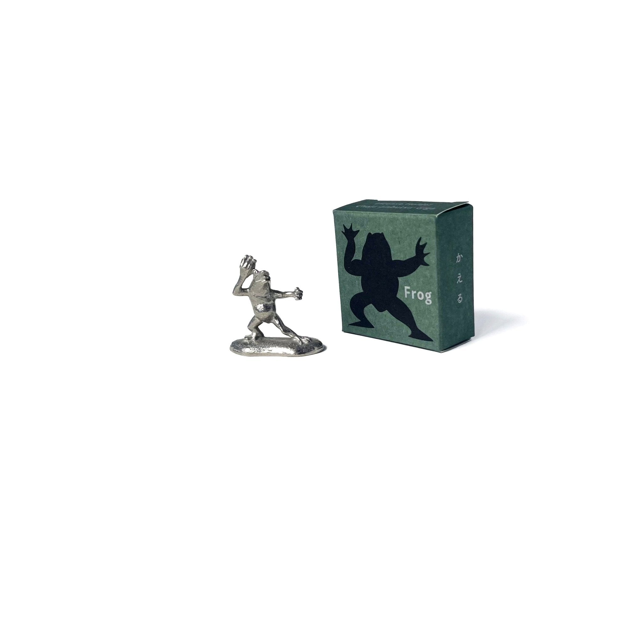 Chōjū-giga pewter incense holder in the shape of a frog with green illustrated box packaging featuring frog silhouette and Japanese text. 
