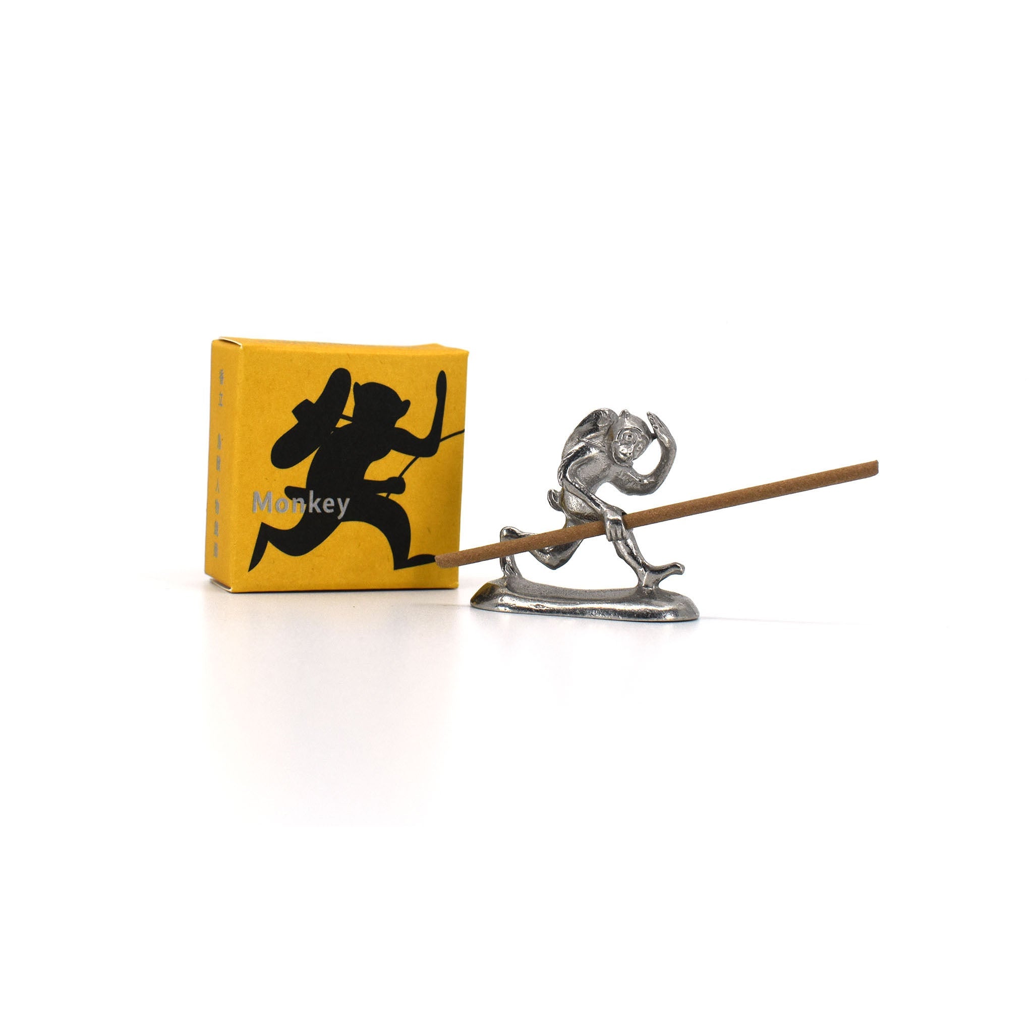 Metal incense holder shaped like a running monkey from the Chōjū-giga scrolls, carrying a backpack and holding a stick of incense, next to a yellow illustrated box labeled “Monkey.”