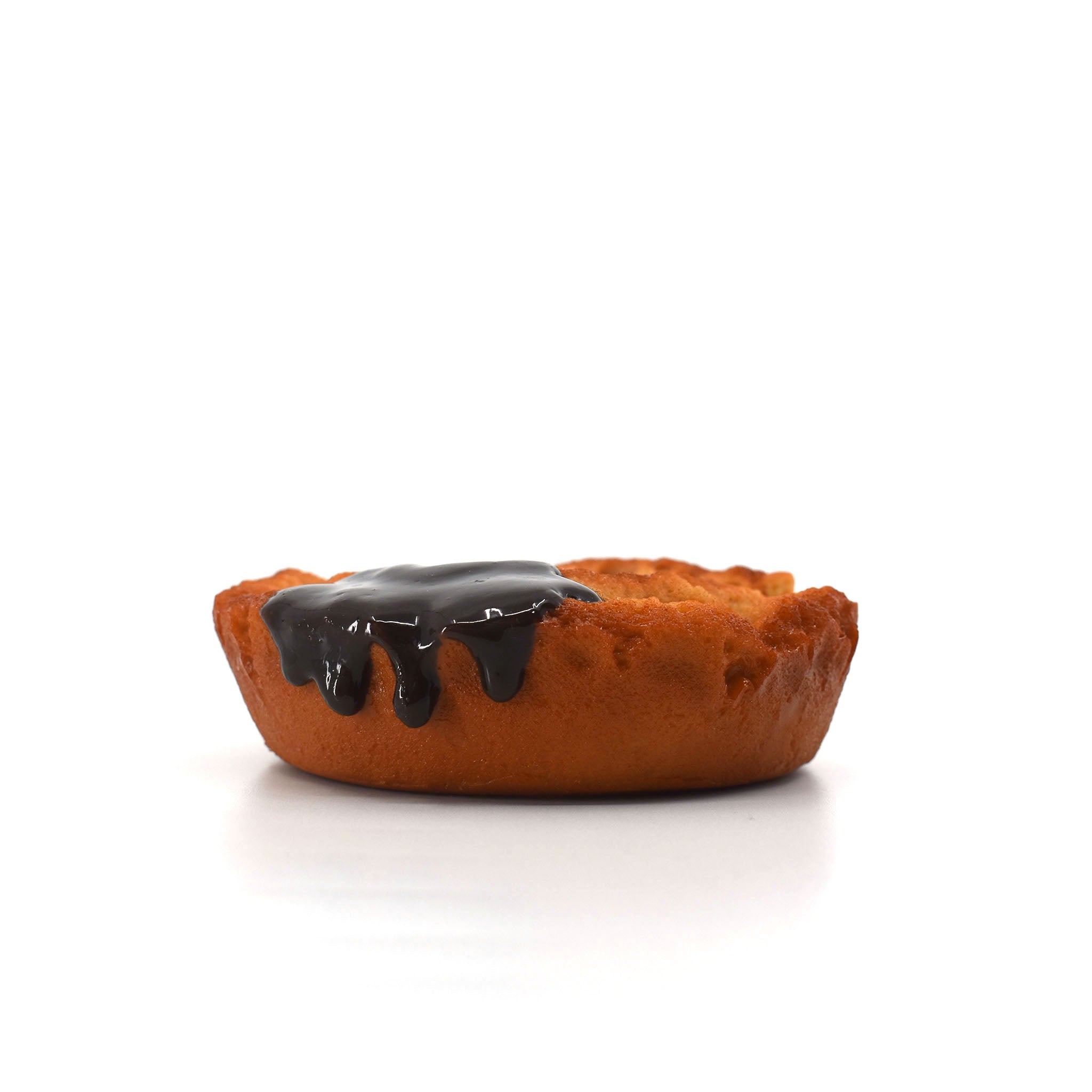 Side view of a realistic donut-shaped phone stand with glossy chocolate glaze dripping down the edge, placed on a white surface.