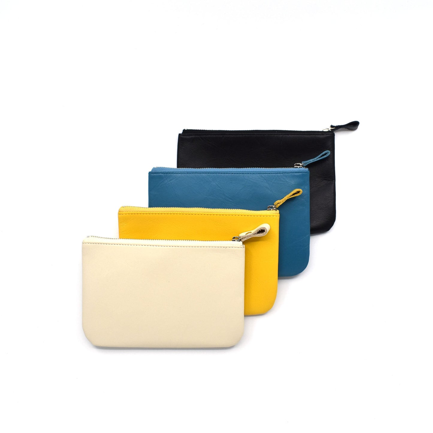 Set of four minimalist leather zip pouches in cream, yellow, blue, and black, stacked neatly on a white background.