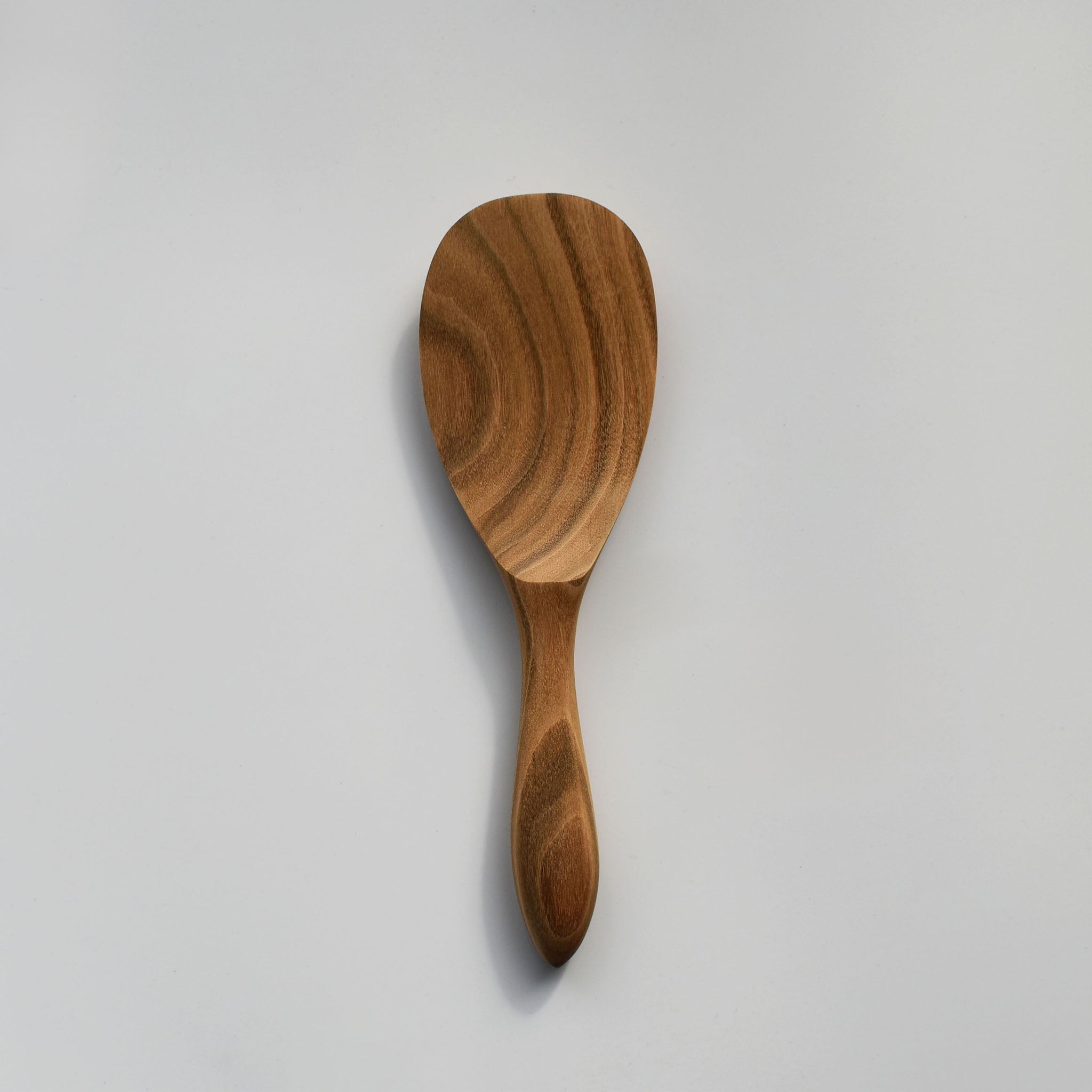 Sakura wood round rice paddle with curved handle, smooth carved bowl, and natural wood grain on a white background