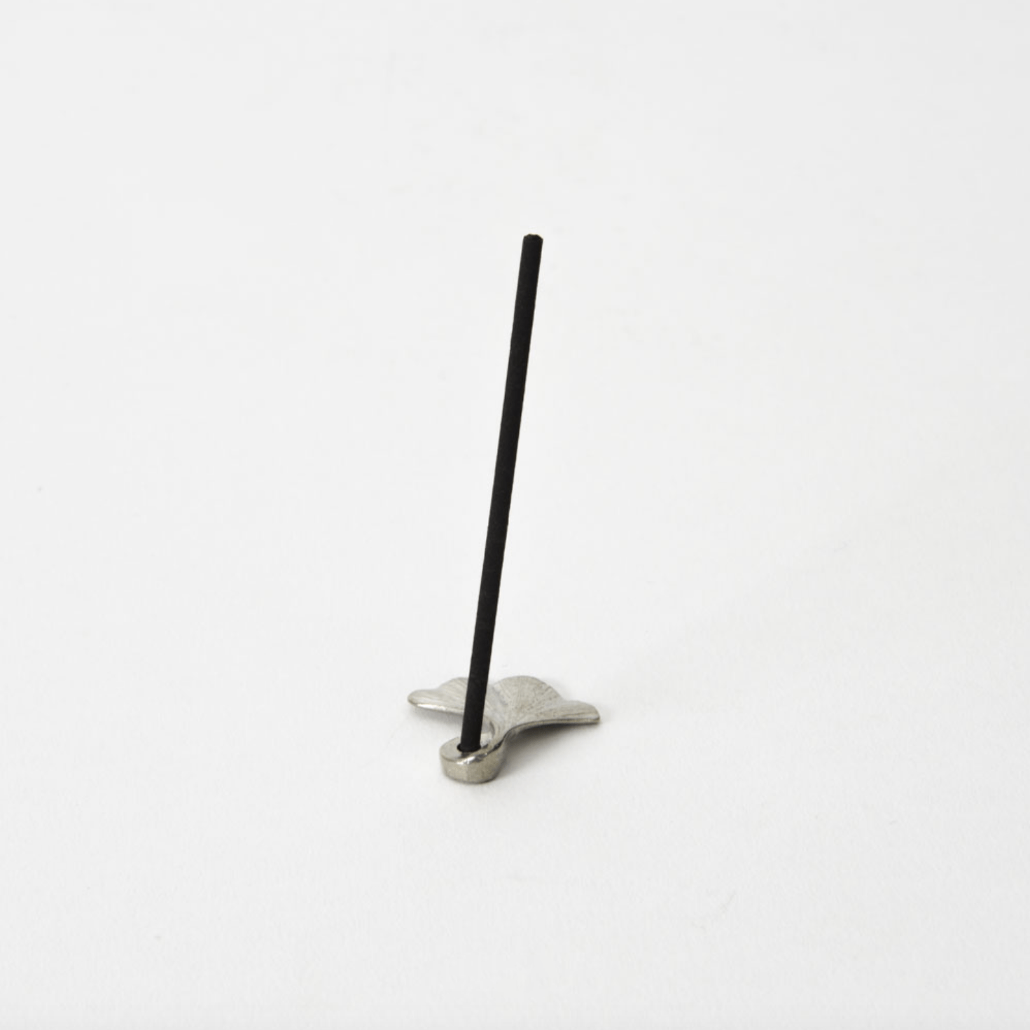 Ginkgo leaf-shaped pewter incense holder with a stick of incense placed upright, photographed on a white background.