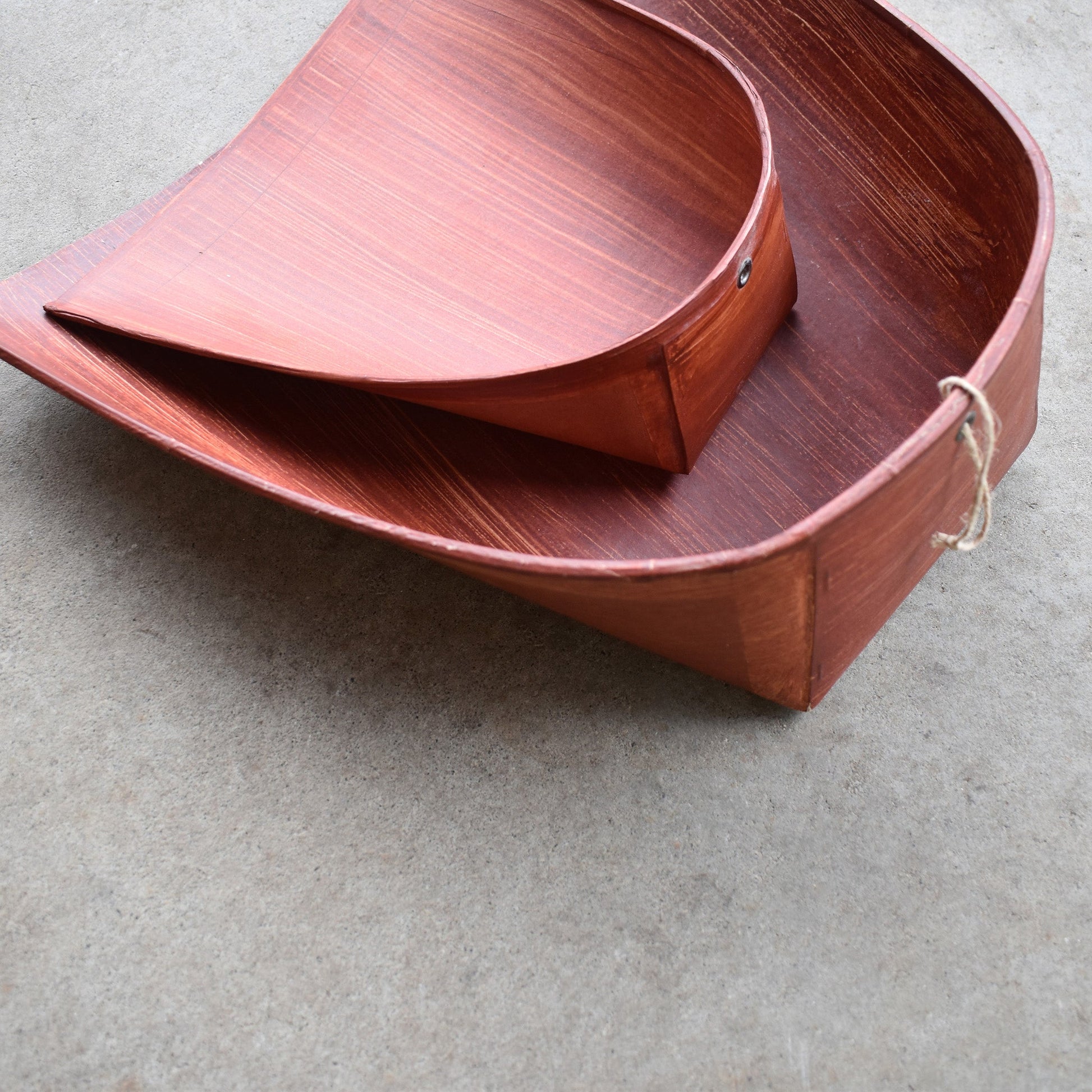 Two stacked Harimi dustpans made from persimmon-tannin-coated washi paper, handcrafted in Japan with curved form and jute hanging string, ideal for static-free sweeping