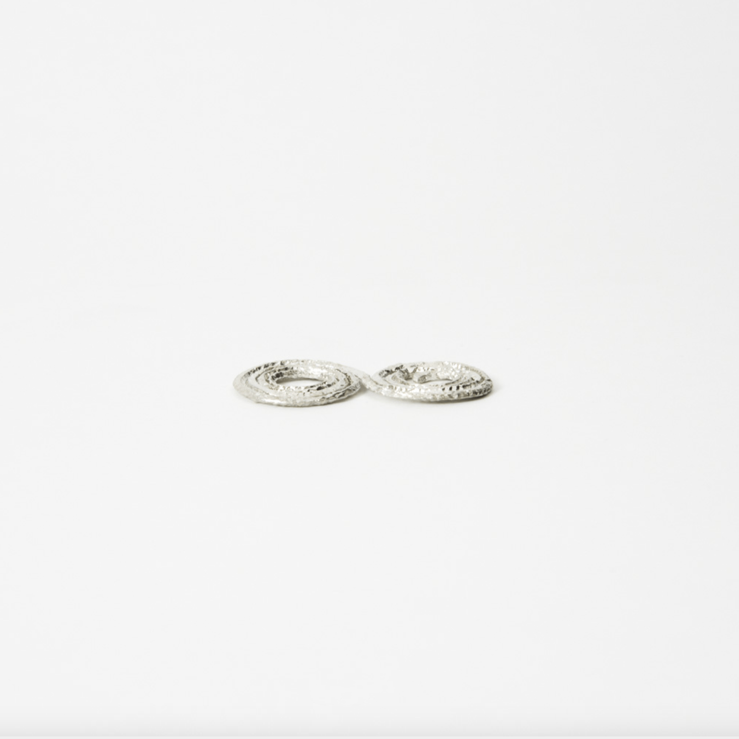 Flow Side angle of lightweight silver coil flower holder showing textured hammered surface and low profile design.
