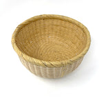 Angled view of a handwoven Japanese bamboo basket with round shape and smooth rim, used for rinsing rice or kitchen storage