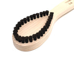 Close-up of the Kanaya lint brush head showing densely packed black bristles in a teardrop shape on a natural wood base, ideal for removing fabric pilling.