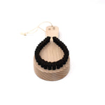 Angled view of the Kanaya lint brush with a natural wood handle and curved black bristles, designed to gently remove fuzz and pilling from delicate fabrics.