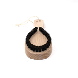 Angled view of the Kanaya lint brush with a natural wood handle and curved black bristles, designed to gently remove fuzz and pilling from delicate fabrics.
