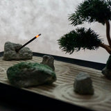 Miniature Zen garden with bonsai and burning incense, representing a Karesansui landscape.