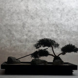Side view silhouette of Karesansui Zen Garden Incense Holder with bonsai tree and stones.