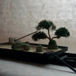 Miniature Karesansui Zen Garden with bonsai tree, burning incense, and bamboo rake.
