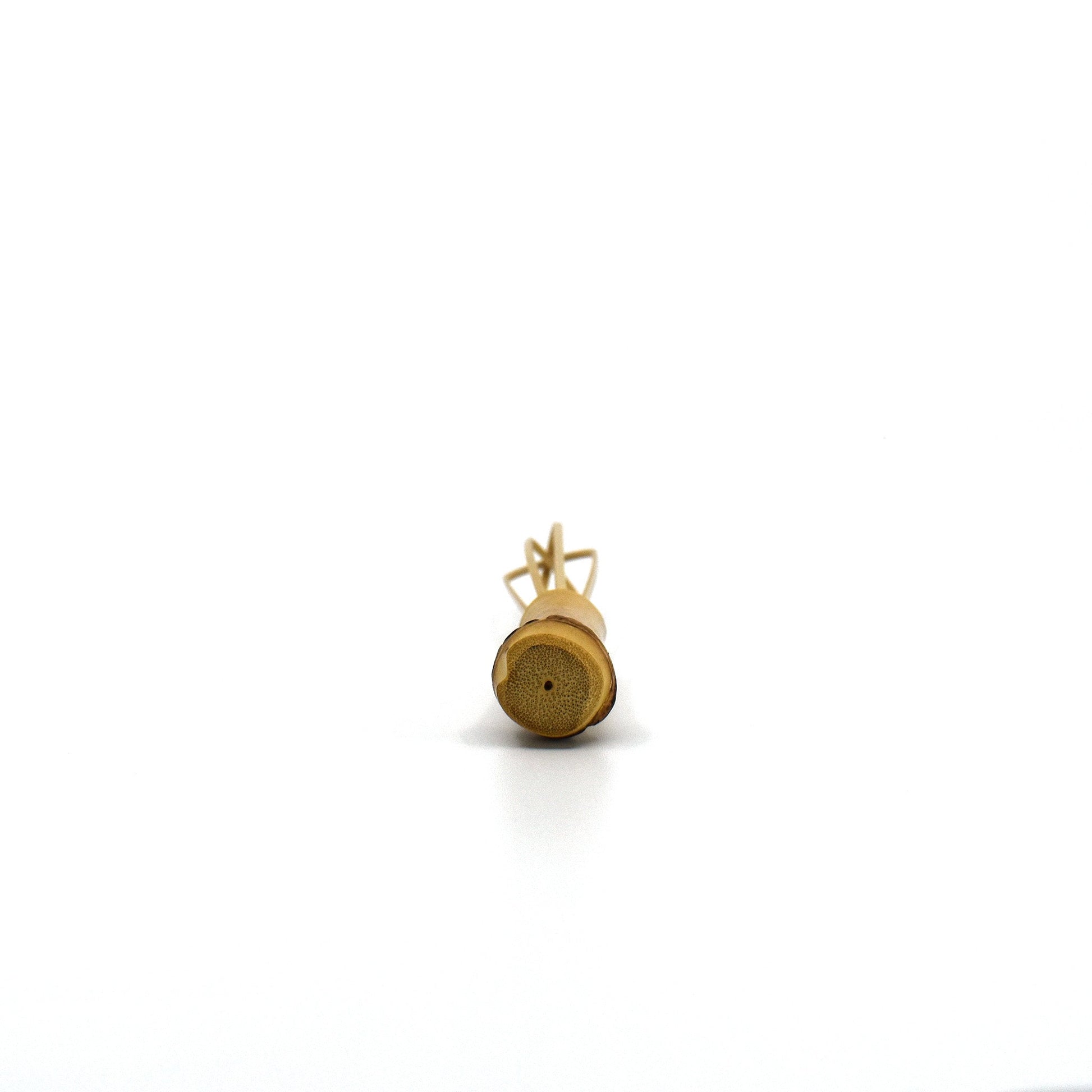 Bottom view of a handcrafted mini bamboo whisk, highlighting its natural bamboo cross-section and curved prongs, used in Japanese cooking and tea preparation.