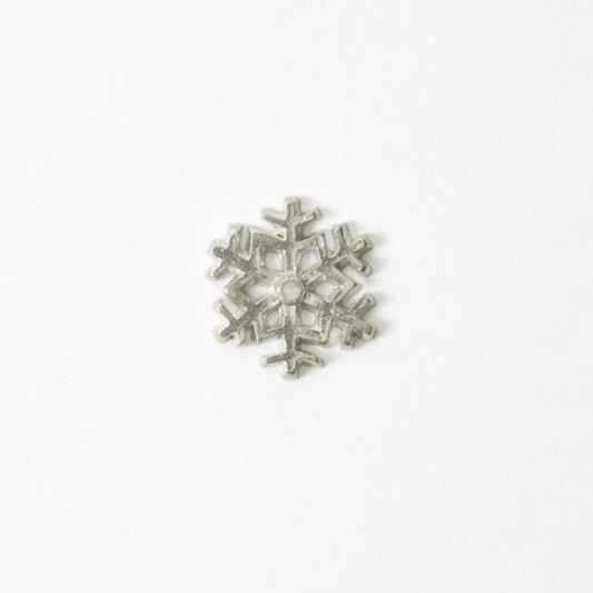 Overhead view of a handcrafted Japanese pewter snowflake incense holder on a white background.