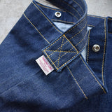 Detailed close-up of Japanese denim shoulder bag showing reinforced yellow stitching, Thread Line Tokyo label, and metal snap button