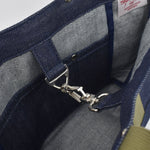 Close-up of interior of Japanese denim tote showing silver snap hook clasp, pocket stitching, and high-quality selvage fabric lining
