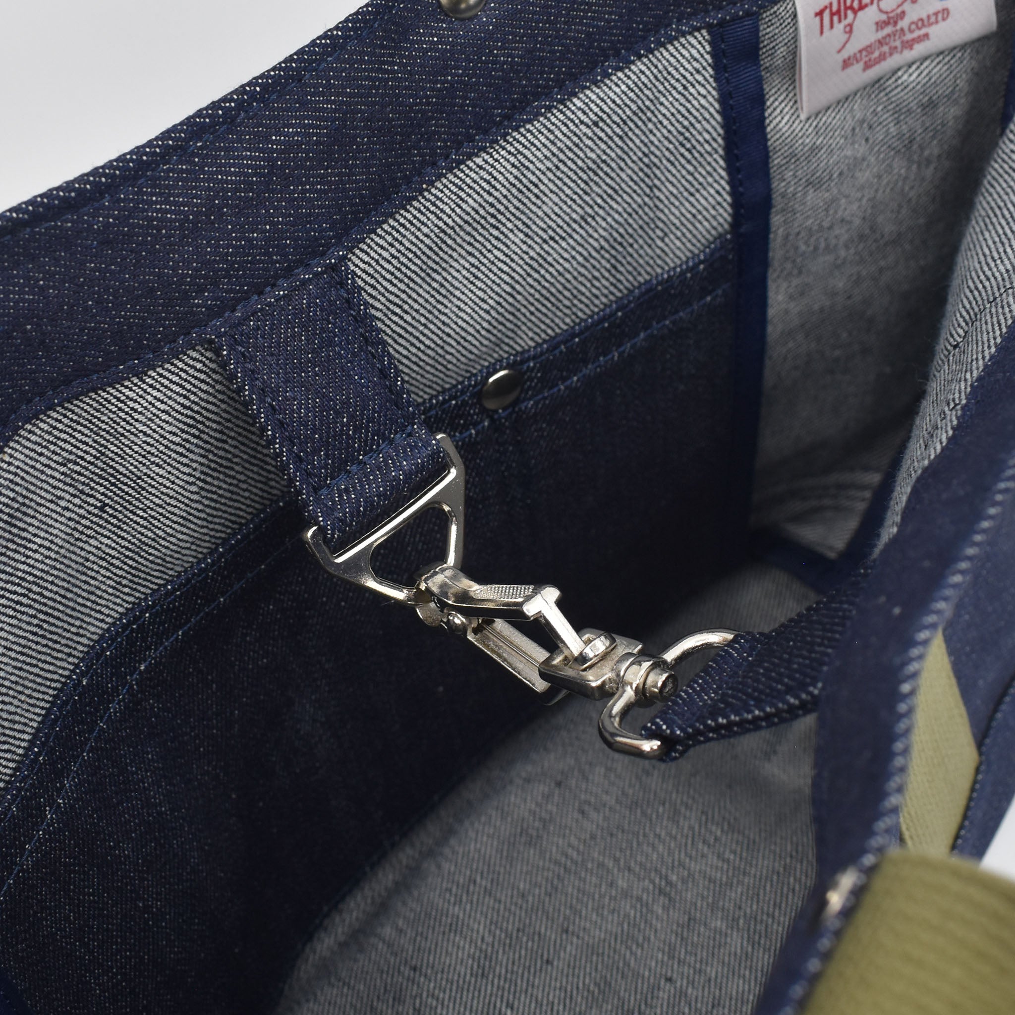Close-up of interior of Japanese denim tote showing silver snap hook clasp, pocket stitching, and high-quality selvage fabric lining