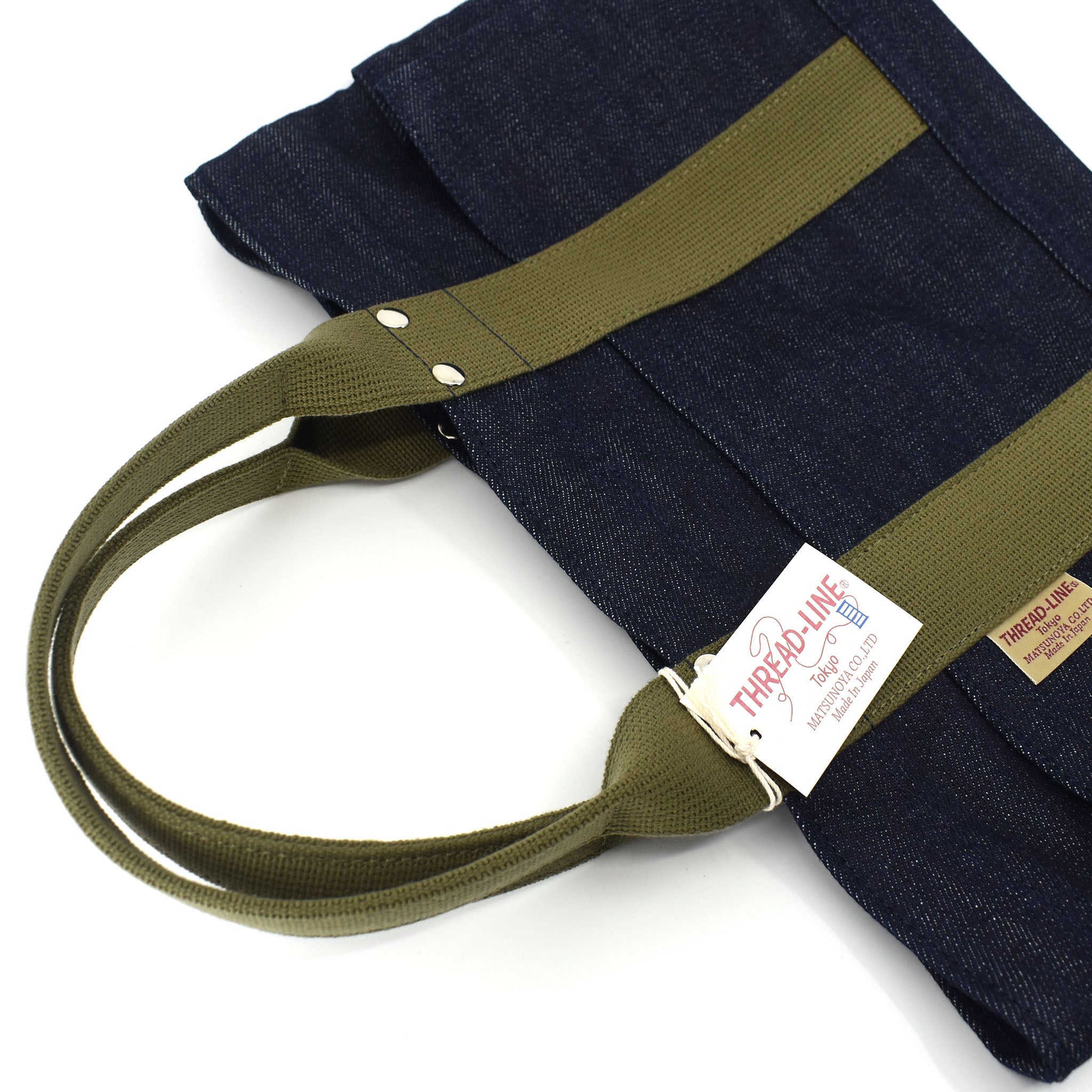 Angled flat lay of Japanese mini denim tote bag with olive webbing handles, silver rivets, and visible Thread Line Tokyo hangtag