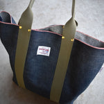 Close-up of Japanese selvage denim tote featuring Thread Line Tokyo label, olive green handles, red stitching, and gold rivets