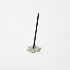 Side view of a silver snowflake-shaped incense holder with a single black incense stick standing upright, displayed on a white background.