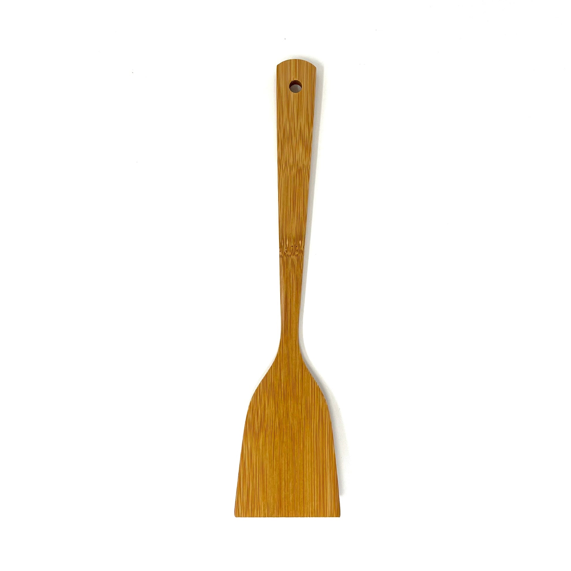 Top-down view of the artisan bamboo cooking turner showing the flat back side of the spatula with a smooth, natural grain finish and a rounded hanging hole at the end of the handle for easy storage.