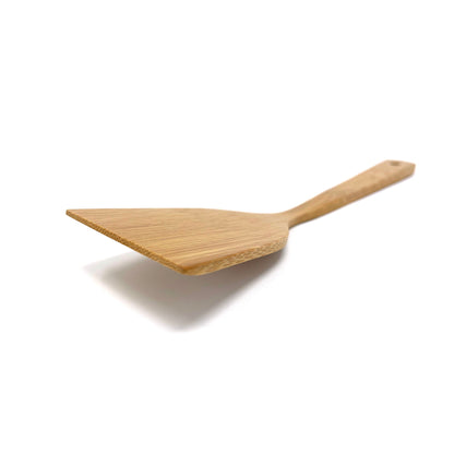 Side-angle close-up of a bamboo cooking turner showcasing its smooth bevel and gently curved ergonomic handle, emphasizing the precision-crafted edge ideal for sliding under delicate foods.