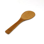 Angled view of a traditional Japanese bamboo rice paddle (shamoji), showcasing its smooth, curved head and ergonomic flat handle—ideal for scooping and mixing freshly steamed rice.