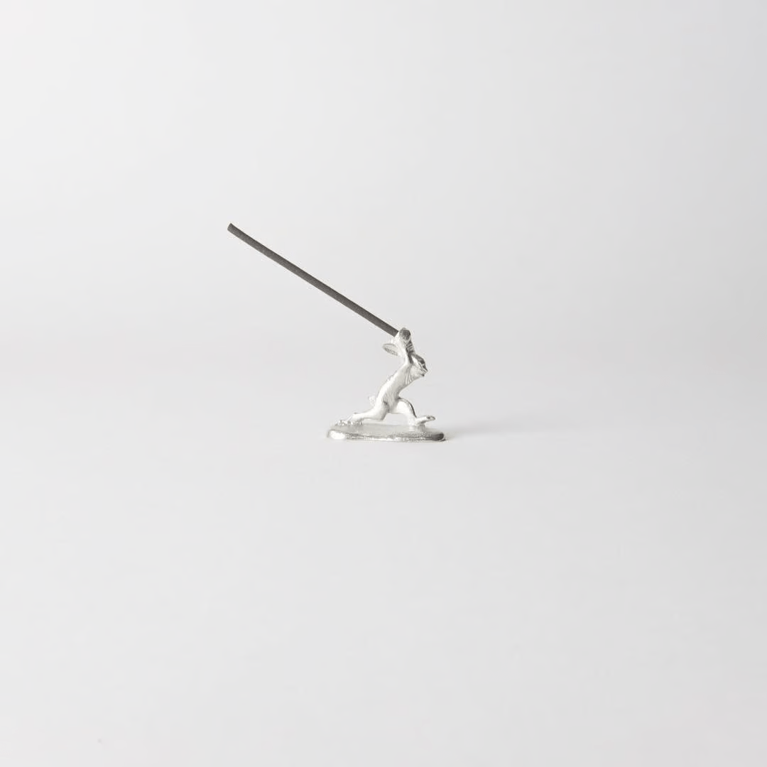 Chōjū-giga rabbit incense holder with incense stick inserted, handcrafted in pewter, capturing the dynamic motion of the leaping rabbit from Japan’s famous animal caricature scrolls.