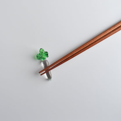 Peach wood chopsticks resting on a glass daikon radish chopstick holder