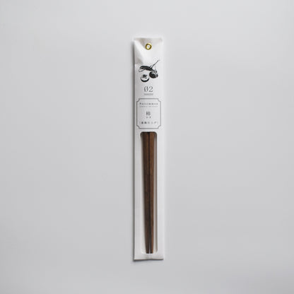 Persimmon wood chopsticks in minimalist white paper packaging with botanical illustration