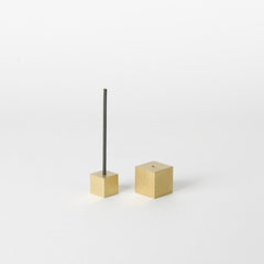 Minimalist gold cube incense holders with a single incense stick, displayed on a light background.