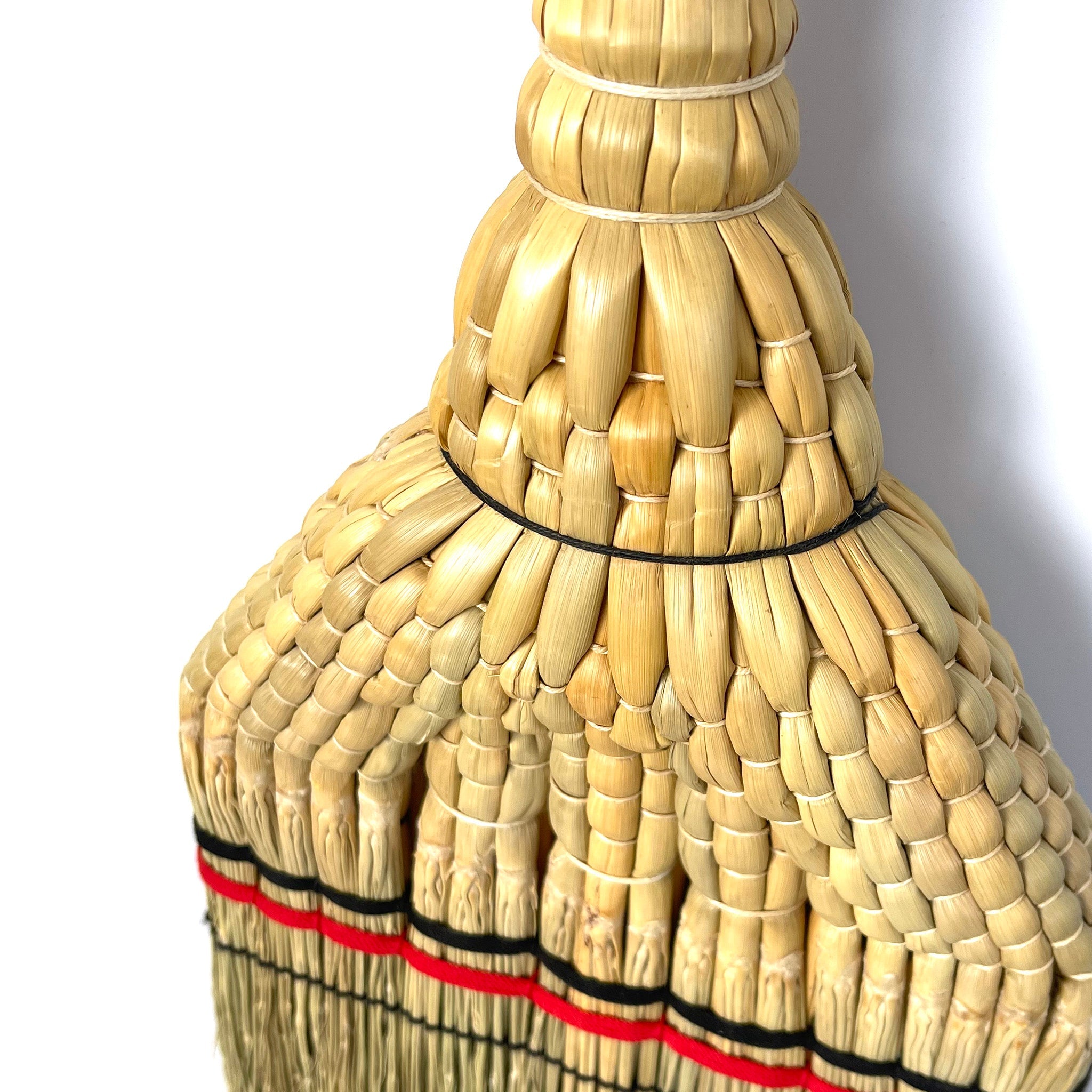 Close-up detail of the intricate handwoven straw pattern on the Shirokiya Denbei Edo Broom, showcasing the craftsmanship, tight braiding, and decorative red and black bands near the base.