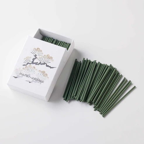 Open box of Hanga Pine incense with green matsu-scented sticks artistically spread on a white surface, showcasing the quantity and traditional Japanese presentation