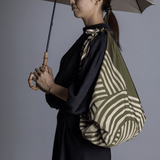 ISA Monyo Yui furoshiki in Rikyu green tied as a shoulder bag, traditional Japanese wrapping cloth styled for everyday use.