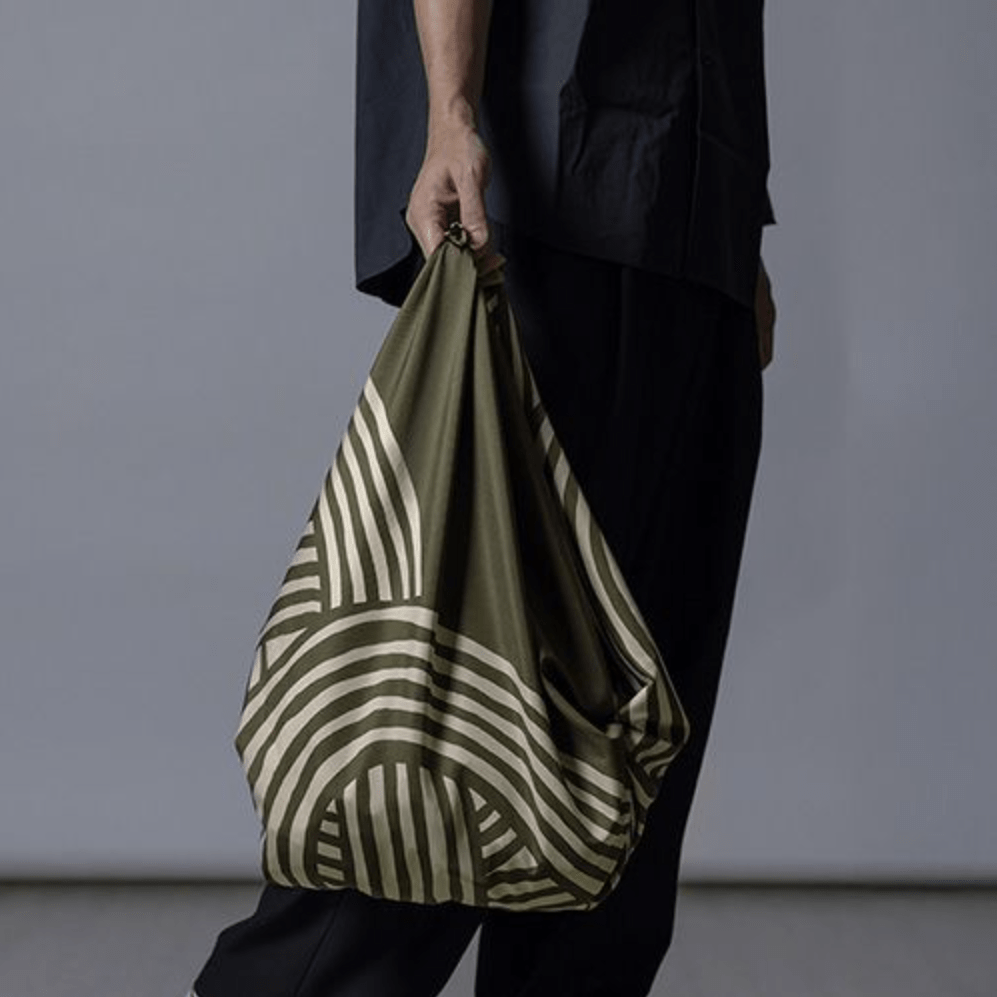 ISA Monyo Yui furoshiki in Rikyu green styled as a hand-carried bag, traditional Japanese wrapping cloth for everyday use.