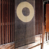 Janome noren curtain with concentric circle motif hanging in a traditional wooden Japanese entryway