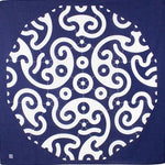 Flat-lay view of traditional Japanese furoshiki cloth featuring bold white swirl and circle patterns on deep indigo background, inspired by classic wave and crest motifs.