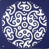Flat-lay view of traditional Japanese furoshiki cloth featuring bold white swirl and circle patterns on deep indigo background, inspired by classic wave and crest motifs.