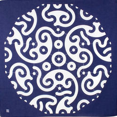 Flat-lay view of traditional Japanese furoshiki cloth featuring bold white swirl and circle patterns on deep indigo background, inspired by classic wave and crest motifs.