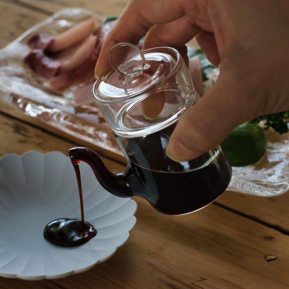 Japanese smooth pour glass soy sauce dispenser pouring soy sauce onto plate, showcasing drip-free spout design.