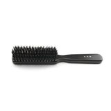 Side profile of a Kanaya medium-stiffness natural bristle hair brush, showcasing densely packed black bristles and a smooth black wooden handle with gold Japanese lettering, placed on a white background.