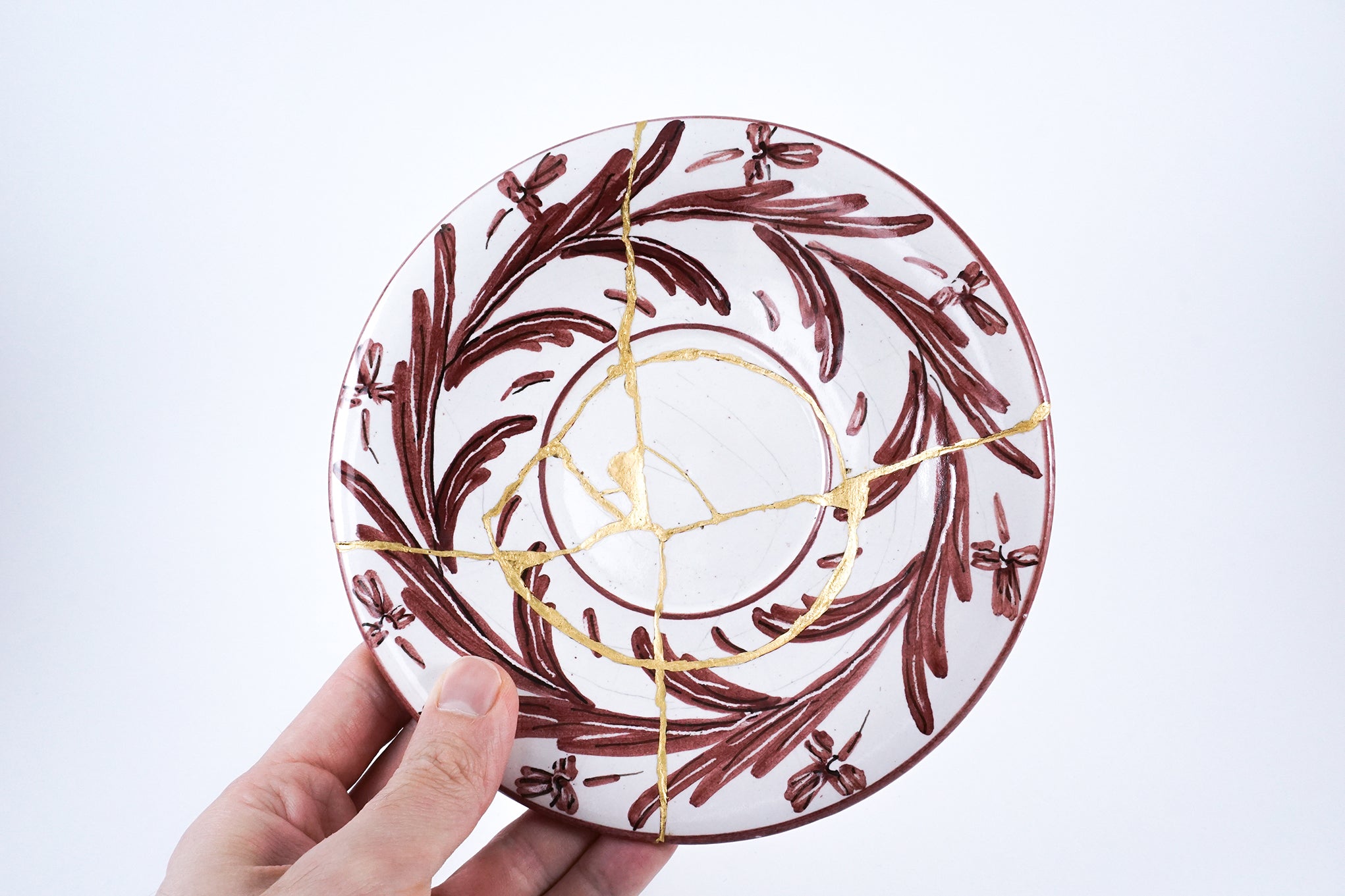 Italian ceramic plate restored using traditional Japanese Kintsugi technique with gold lacquer, highlighting cross-cultural beauty in mended design.