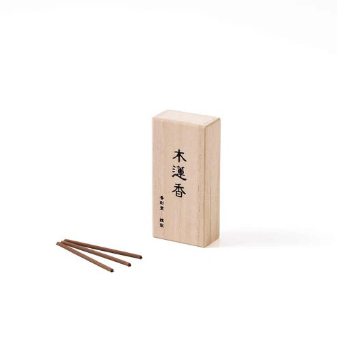 Box of Koto no Kou Magnolia Incense with three brown incense sticks laid beside it on a white background