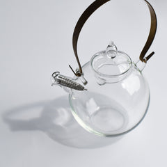 Manmaru glass teapot with a round body and brass handle, featuring a built-in stainless steel strainer, handblown for an elegant Japanese tea experience.