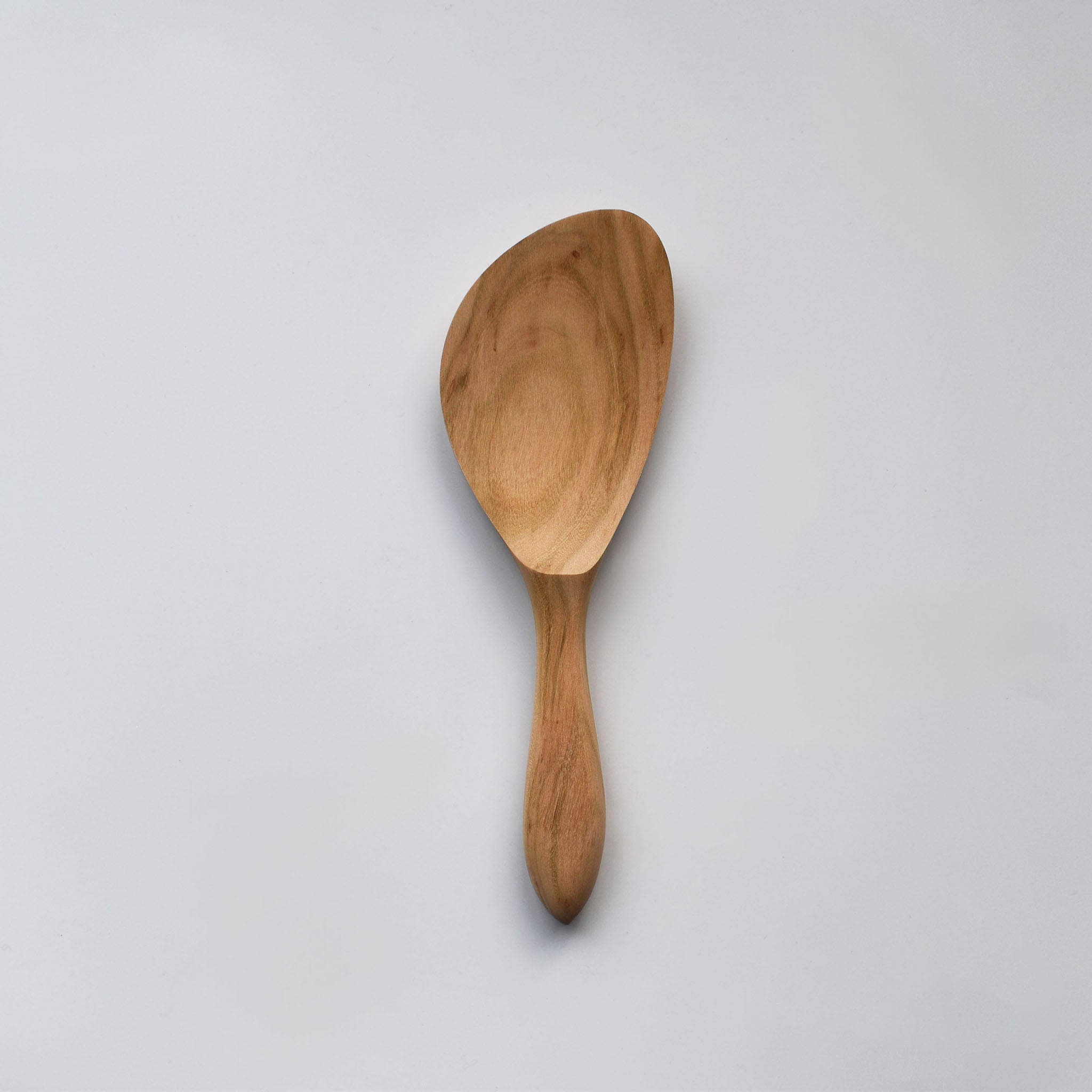 Sakura wood angled rice paddle with smooth carved bowl, curved handle, and natural wood grain on a white background