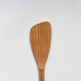 Close-up of the Sakura wood angled spatula showing the curved paddle head and natural wood grain