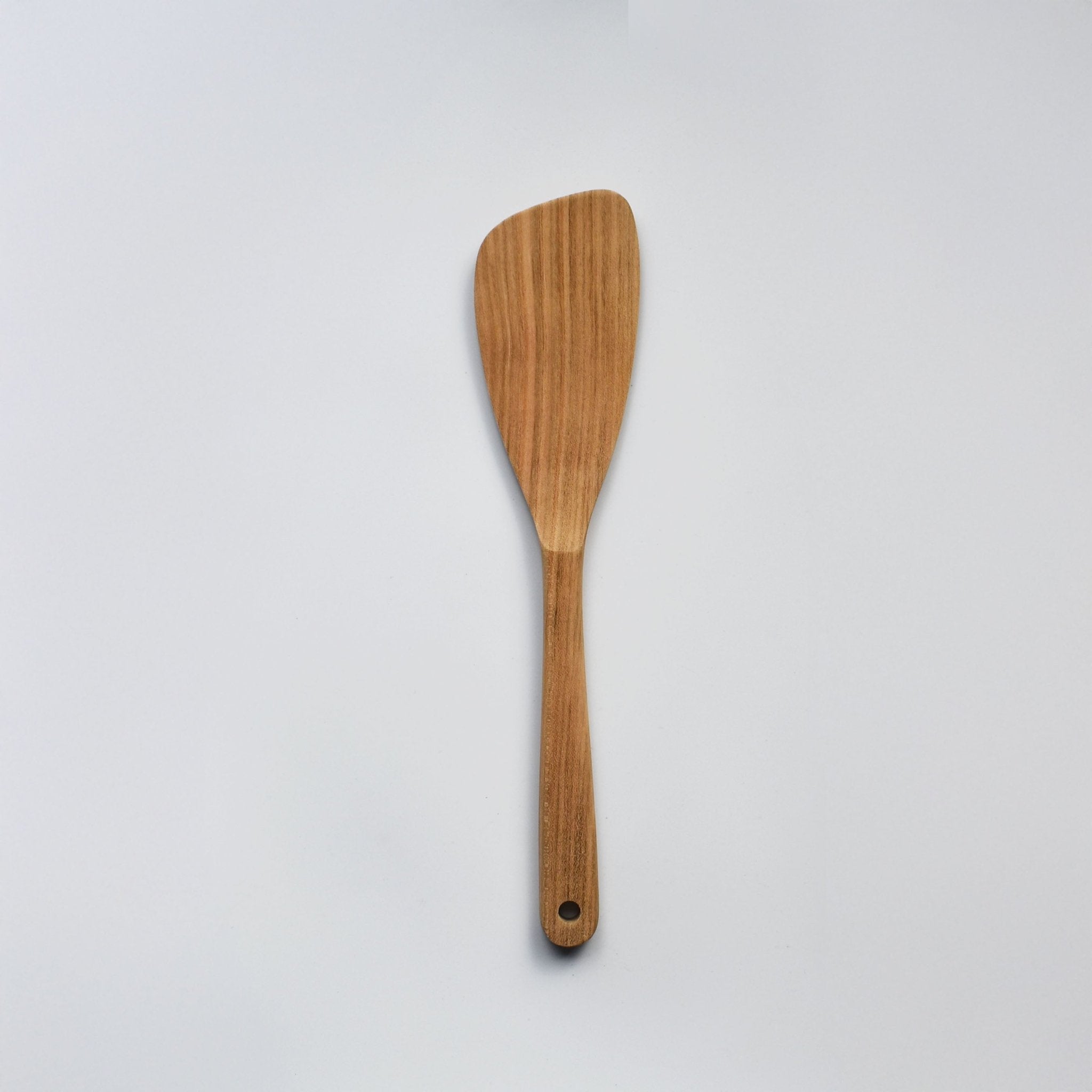 Sakura wood angled spatula with curved paddle shape, hanging hole, and natural wood grain on a white background